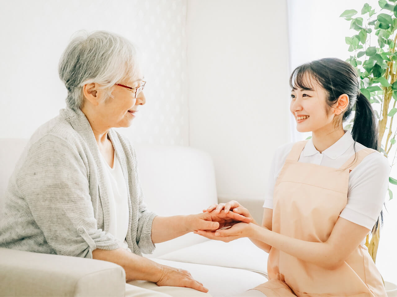 高齢女性と看護師が手を取り合い、笑顔で会話する様子