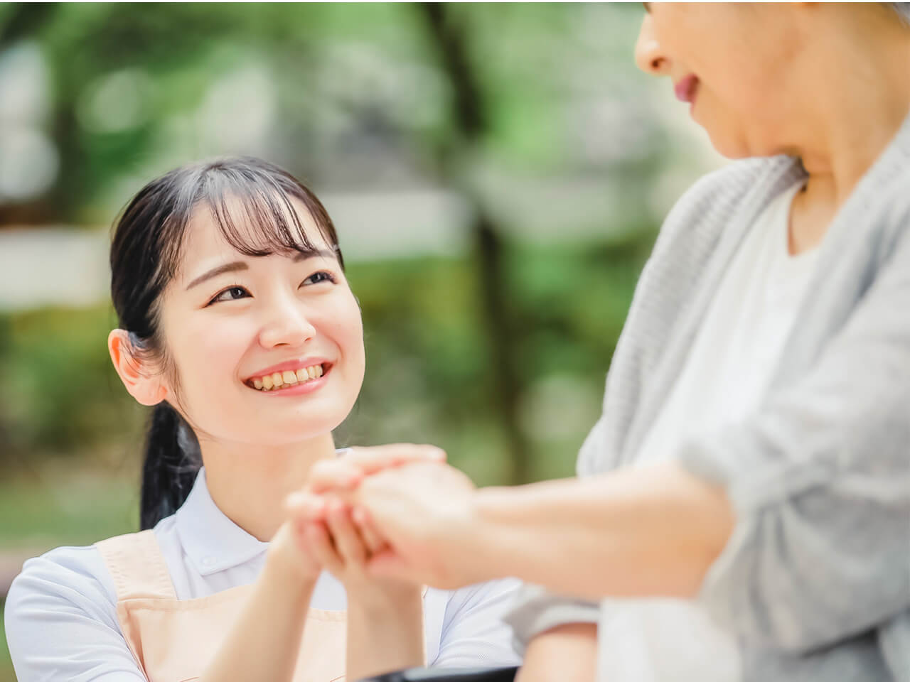 看護師が屋外で利用者の手を取り、穏やかに寄り添う様子